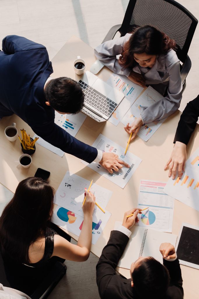 Overhead view of a team of accountants collaboratively working at a table, using digital tools supported by IT services.