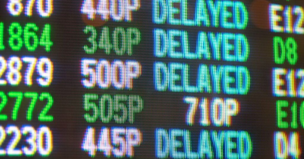 An airport flight information screen showing numerous delayed flights, attributed to a global IT outage caused by a CrowdStrike update.