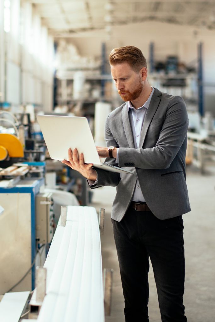 An IT professional conducting a survey within a factory setting, examining technological integrations and workflows.