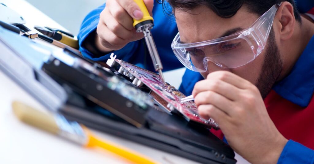 Technician soldering a motherboard with precision at IT GOAT, showcasing expert hardware repair services.